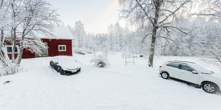 Person kehrt vom Dach eines Autos mit einem Besen den Schnee ab
